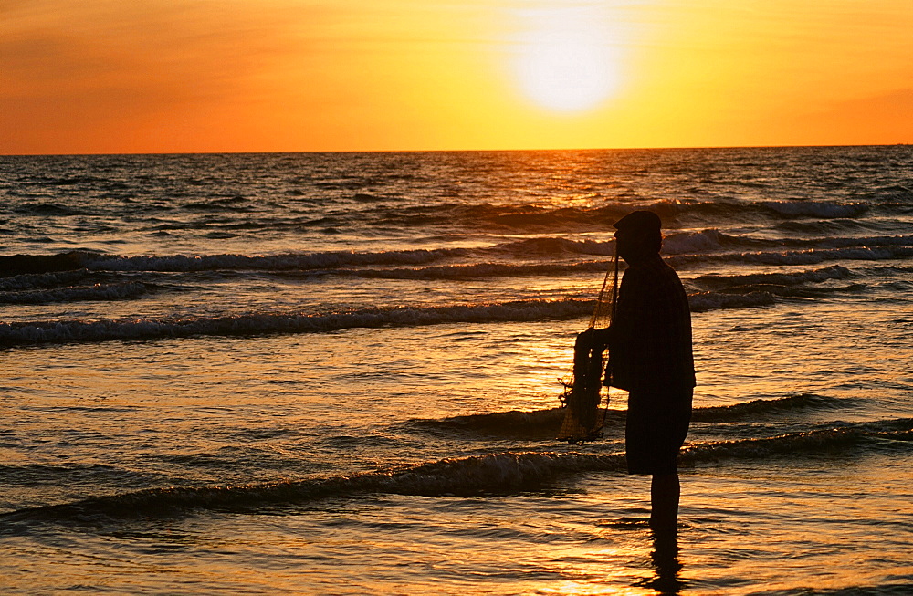 A fisherman with a throw net at sunset, Spain, Europe