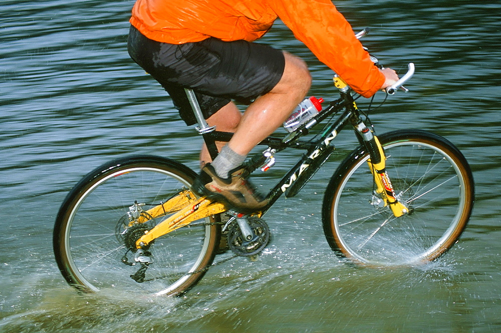 A mountain biker riding through Rydal Water in the Lake District, Cumbria, England, United Kingdom, Europe