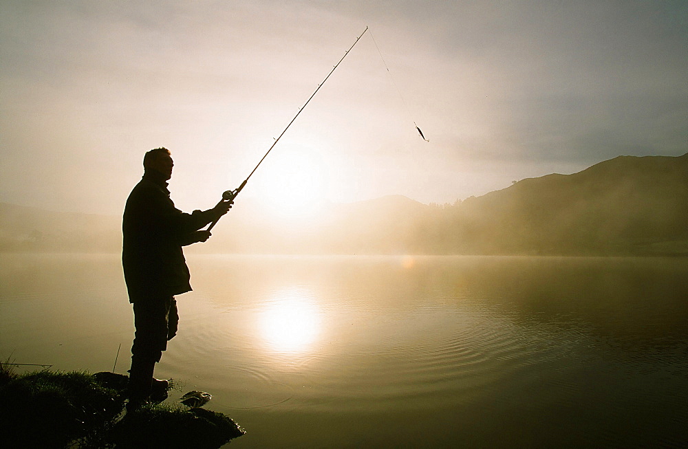 A fisherman on Rydal Water at dawn in the Lake District, England, United Kingdom, Europe