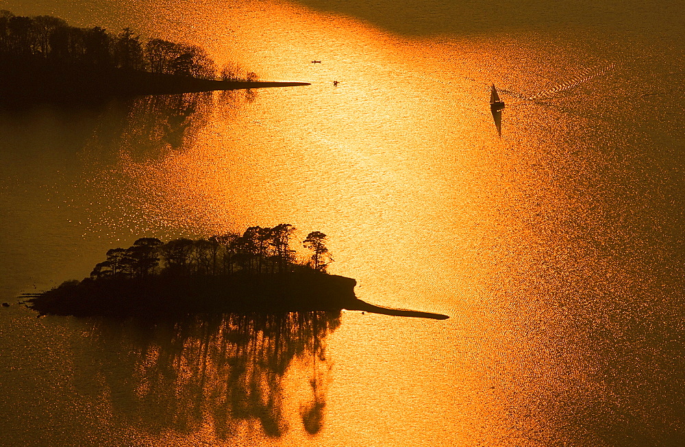 A canoe and sailing boat on Derwent Water at sunset in the Lake District National Park, Cumbria, England, United Kingdom, Europe