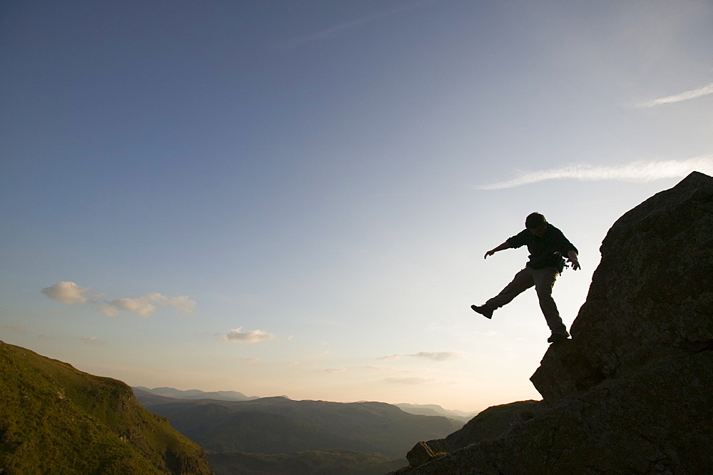 A climber balancing on a crag above Thirlmere in the Lake District, Cumbria, England, United Kingdom, Europe