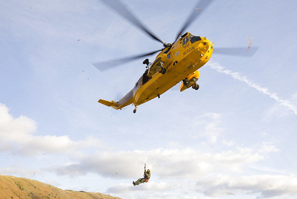 An RAF Sea King helicopter evacuates a seriuosly injured climber with a broken femur from a mountain rescue site in the Langdale Valley, Lake District, England, United Kingdom, Europe