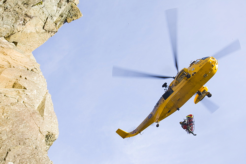 An RAF Sea King helicopter evacuates a seriuosly injured climber with a broken femur from a mountain rescue site in the Langdale Valley, Lake District, England, United Kingdom, Europe