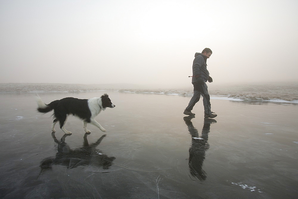 A walker on a frozen tarn near the summit of Caudale Moor in the Lake District National Park, Cumbria, England, United Kingdom, Europe