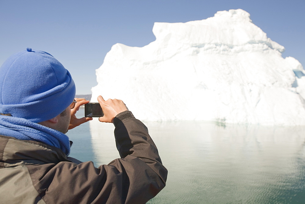 A tourist photographs an iceberg from the Jacobshavn glacier (Sermeq Kujalleq), Greenland, Polar Regions