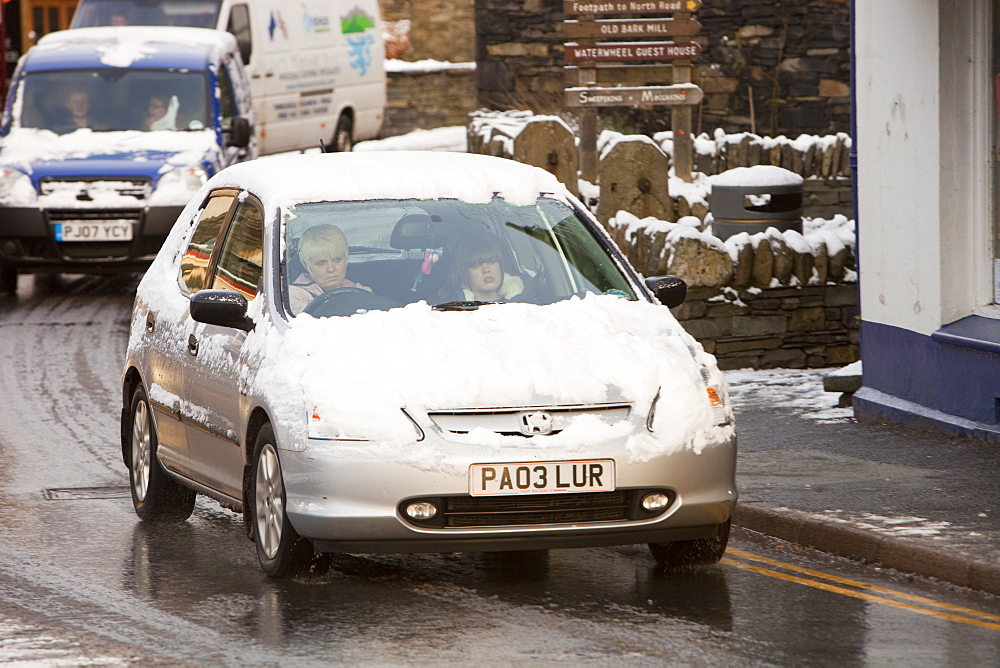 Car driving through Ambleside in the snow, Lake District, Cumbria, England, United Kingdom, Europe