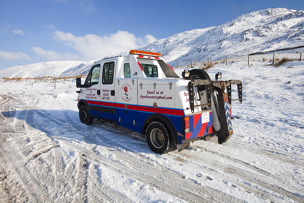 A break down recovery vehicle in winter snow on Kirkstone Pass in the Lake District, Cumbria, England, United Kingdom, Europe