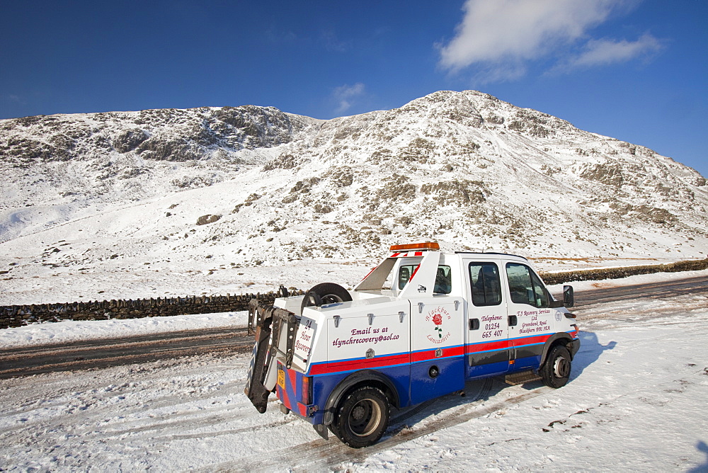 A break down recovery vehicle in winter snow on Kirkstone Pass in the Lake District, Cumbria, England, United Kingdom, Europe