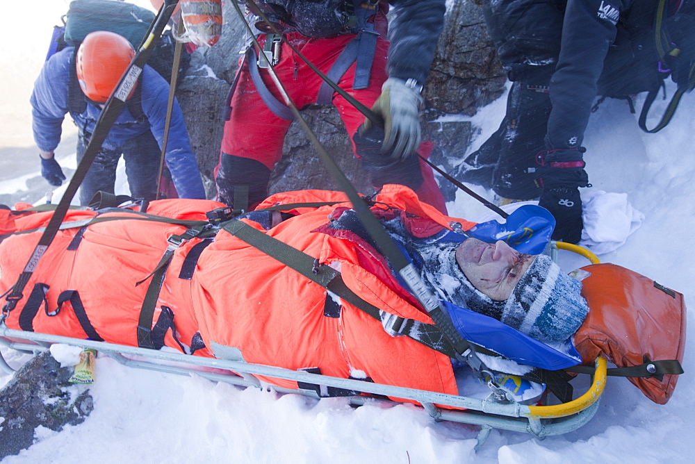 A Navy Sea King helicopter crew and mountain rescue team members treat a seriously injured walker who had fallen 250 , Cumbria, England, United Kingdom, Europe