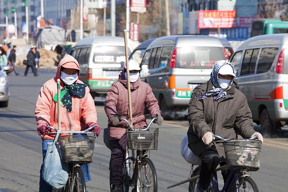 Road sweepers on bicycles wear face masks against the awful air pollution in Suihua city, Heilongjiang, Northern China, Asia