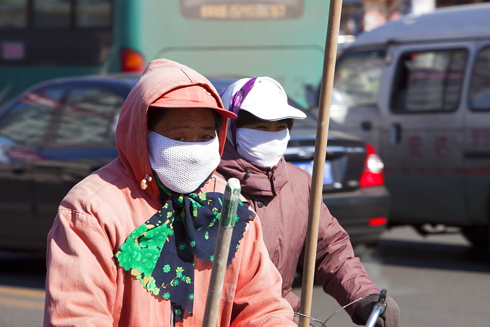 Road sweepers on bicycles wear face masks against the awful air pollution in Suihua city, Heilongjiang, Northern China, Asia