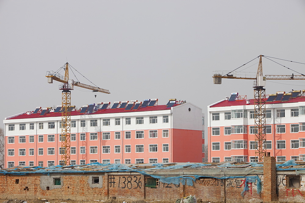 New apartment block replaces old slum dwellings, all with solar water heaters on the roof, in Heilongjiang province, Northern China, Asia