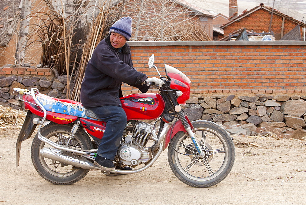 A Chinese man on a motorbike in Heilongjiang province in Norhern China, Asia