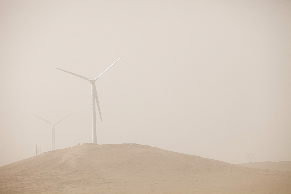 A wind farm in Inner Monolia produces green electric through the haze of a dust storm, China, Asia