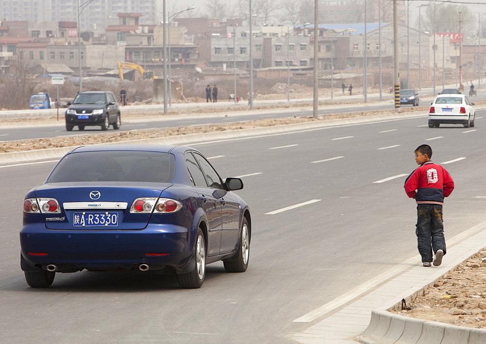 A young boy stares at a passing car in Xian city, Northern China, Asia