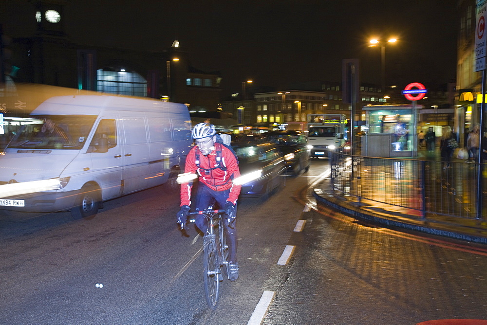 A cyclist at night outside Kings Cross, London, England, United Kingdom, Europe