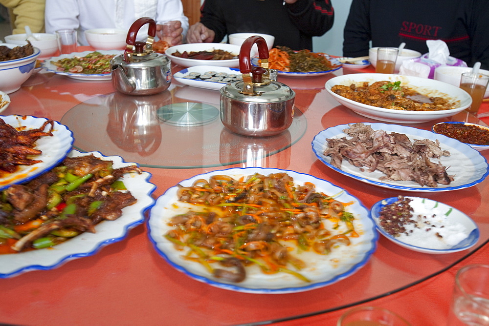 Chinese people sit down for a meal in a restaurant which includes several dishes of dog meat, China, Asia