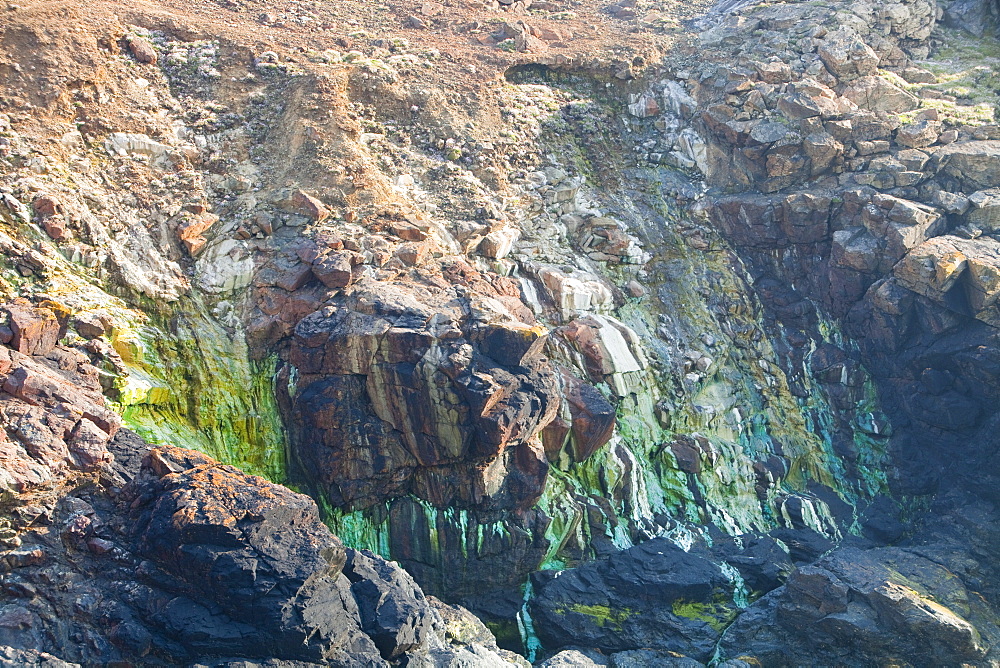 Sea cliffs stained green from copper deposits leaching from the old Geevor Tin Mine near St. Just in Cornwall, England, United Kingdom, Europe