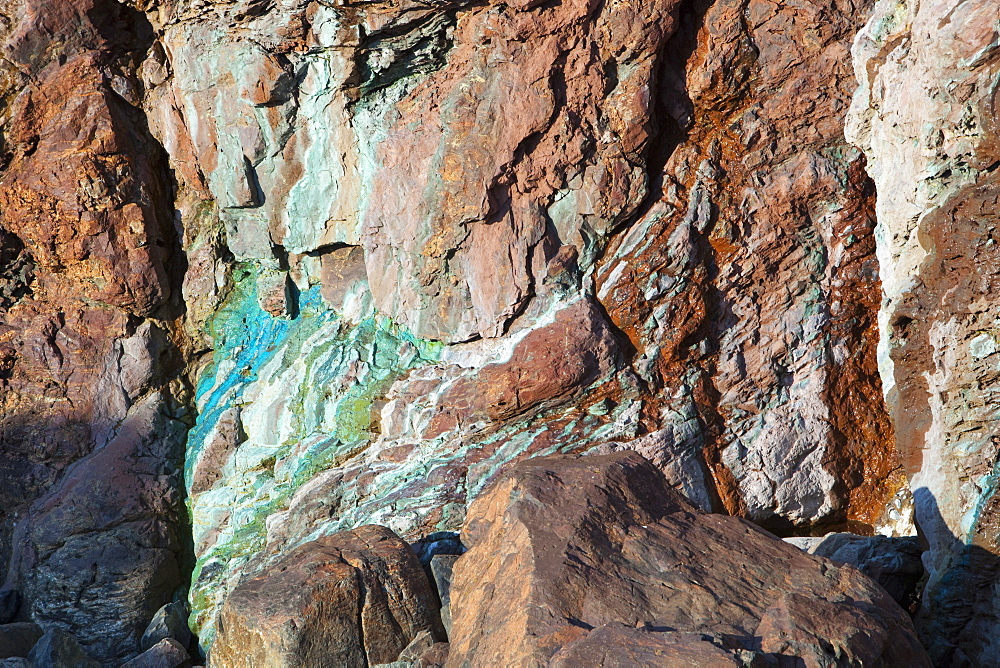 Sea cliffs stained green from copper deposits leaching from the old Geevor Tin Mine near St. Just in Cornwall, England, United Kingdom, Europe