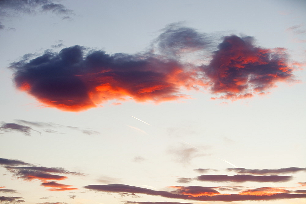 A plane flying through sunset clouds over Ambleside, Cumbria, England, United Kingdom, Europe