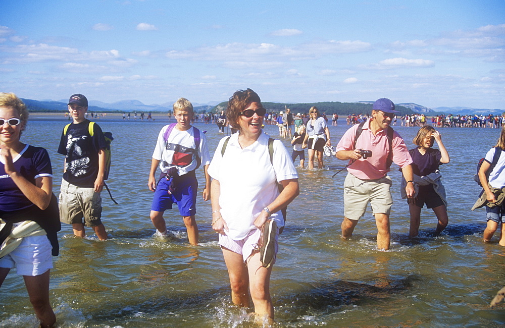 People crossing Morecambe Bay at low tide on a sponsored walk being led by Cedric Robinson, the Queen's offical guide to the treacherous sands of Morecambe Bay, Lancashire, England, United Kingdom, Europe