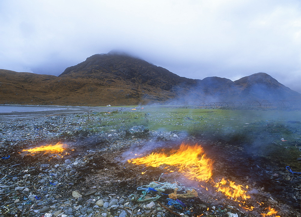 Burning plastic rubbish washed up on a beach on the Isle of Skye near Elgol, Scotland, United Kingdom, Europe