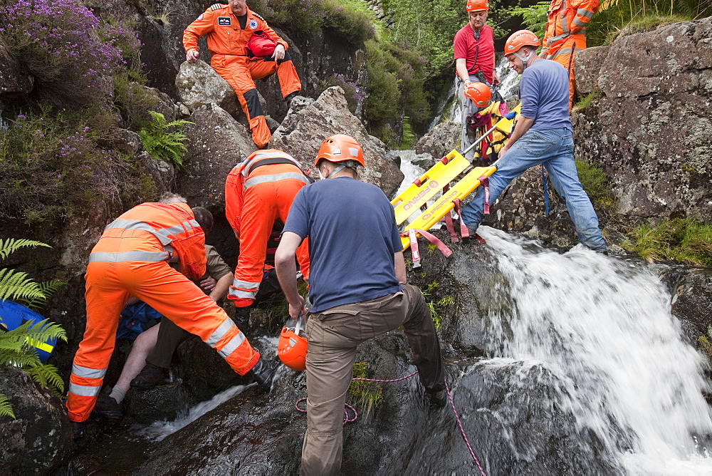 Paramedics from the Great North Air Ambulance and members of Langdale/Ambleside Mountain Rescue Team treat an injured man who fell into Wrynose Beck, before transferring him to hospital via helicopter. Lake District, Cumbria, England, United Kingdom, Europe