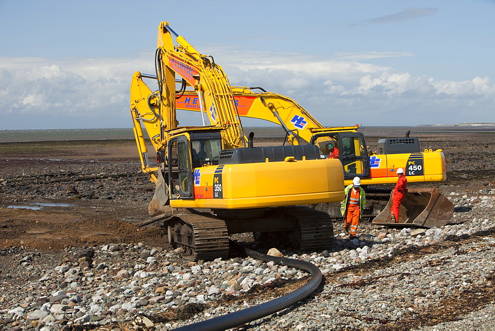 Construction workers installing a power cable on the foreshore of the Solway Firth near Workington, Cumbria, England, United Kingdom, Europe