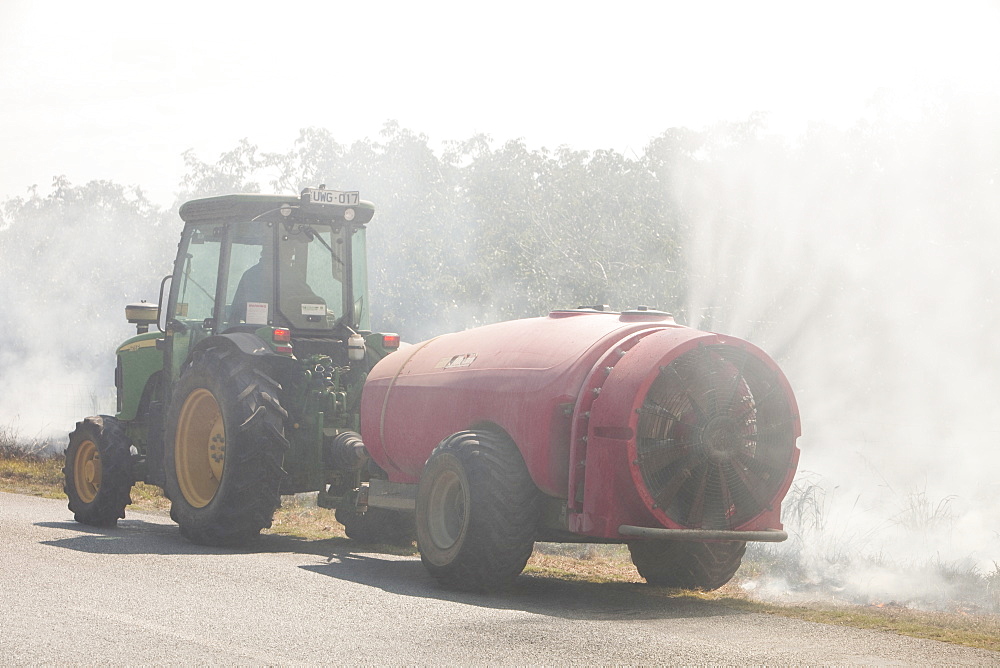 A farmer tackles a roadside fire probably started by a motorist throwing a cigarette out of the window, near Shepperton, Victoria, Australia, Pacific