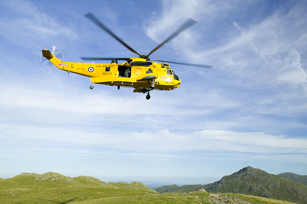 A helicopter comes to evacuate an injured walker on Bow Fell in the Lake District. Cumbria, England, United Kingdom, Europe