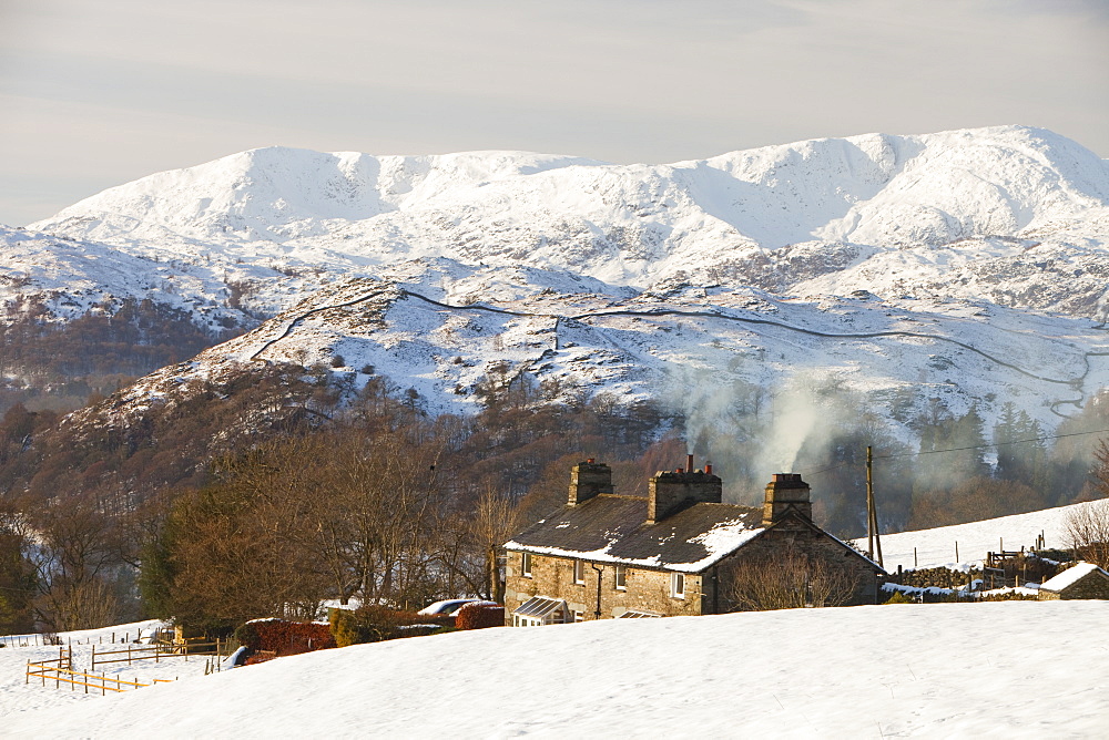 A cottage in Ambleside with the Coniston Fells in winter snow in the Lake District, Cumbria, England, United Kingdom, Europe