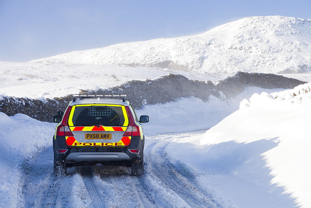 A Police car tries to get over the Kirkstone Pass road above Windermere after it is blocked by spindrift and wind blown snow, Lake District, Cumbria, England, United Kingdom, Europe