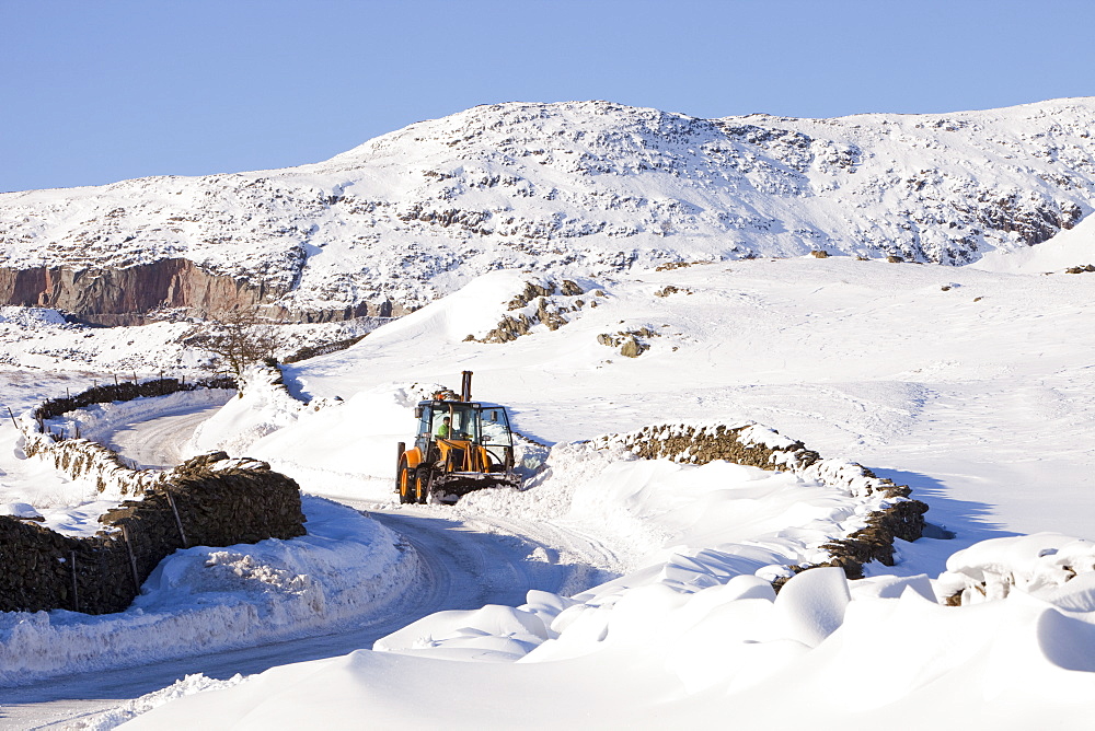 Charlie Middleton, an employee of Cumbria County Council clears snow from the blocked Kirkstone Pass, the highest mountain pass in the Lake District, Cumbria, England, United Kingdom, Europe