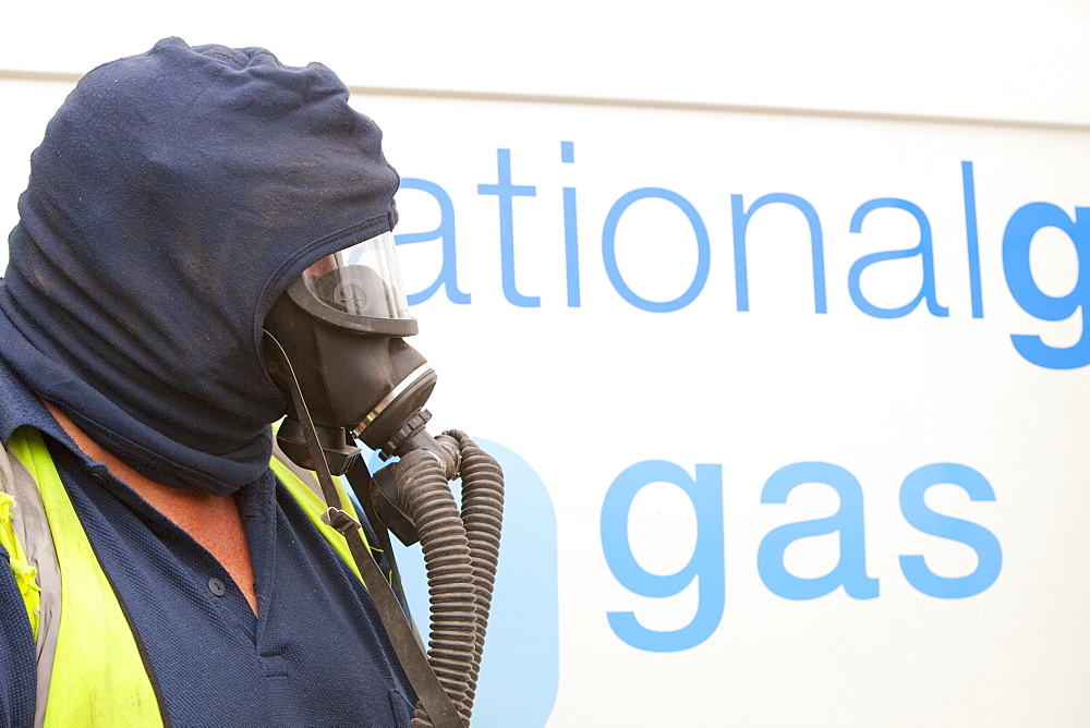 A Britiush Gas worker wears protective gas mask prior to cutting through the gas main as part of an upgrade of piping, Ambleside, Cumbria, England, United Kingdom, Europe