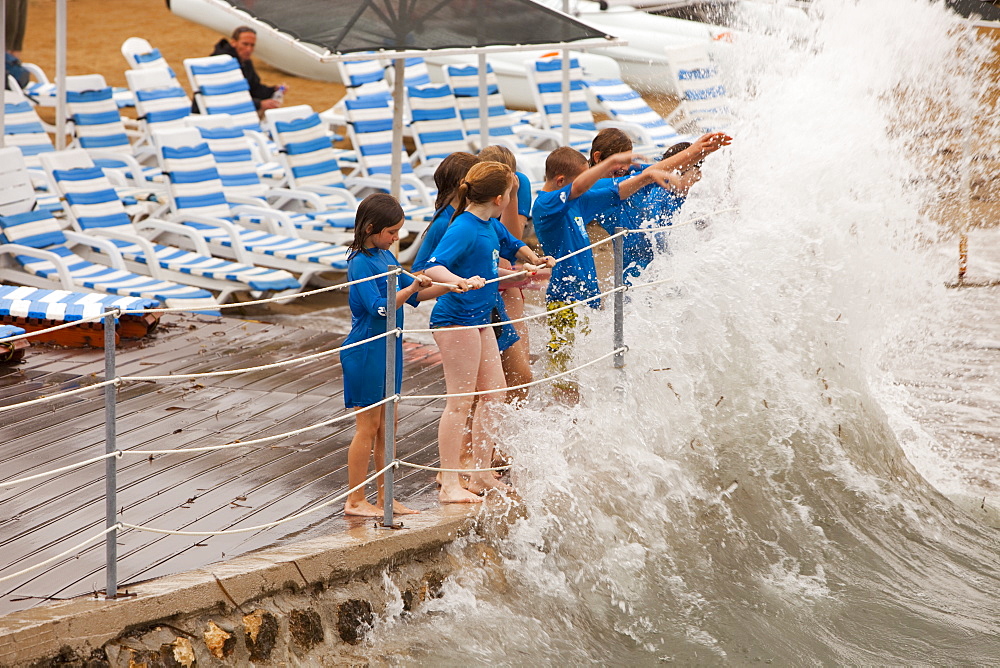 Children dodging storm waves at a holiday resort in Teos, Western Turkey, Eurasia