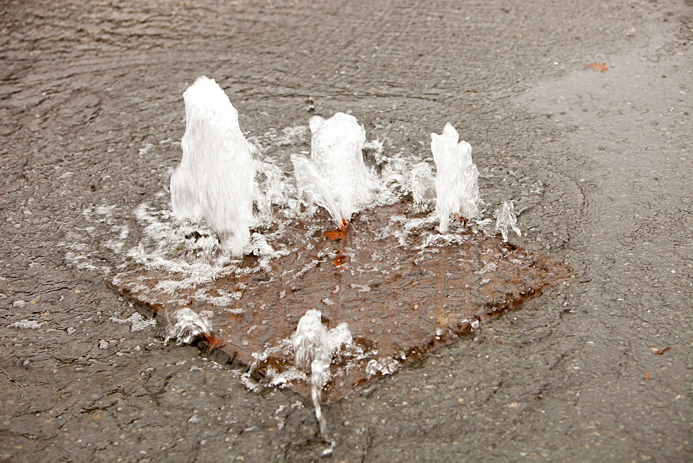 Pressure of the floodwater bubbling up through a man hole cover in Ambleside, Cumbria, England, United Kingdom, Europe