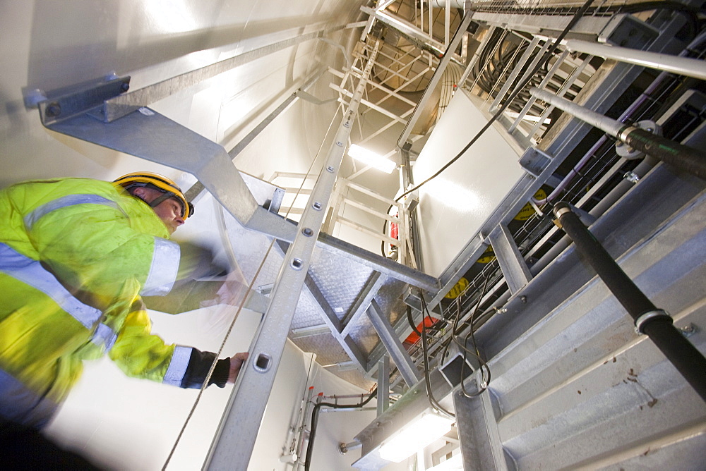 An engineer climbs the ladder of a Siemens wind turbine tower, destined for the Walney offshore wind farm, Wales, United Kingdom, Europe