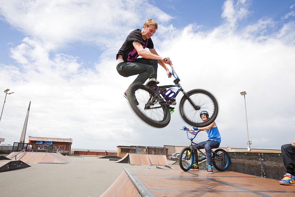 Teenage boys perform aerial stunts on BMX bikes at a BMX park in Rhyl, North Wales, United Kingdom, Europe