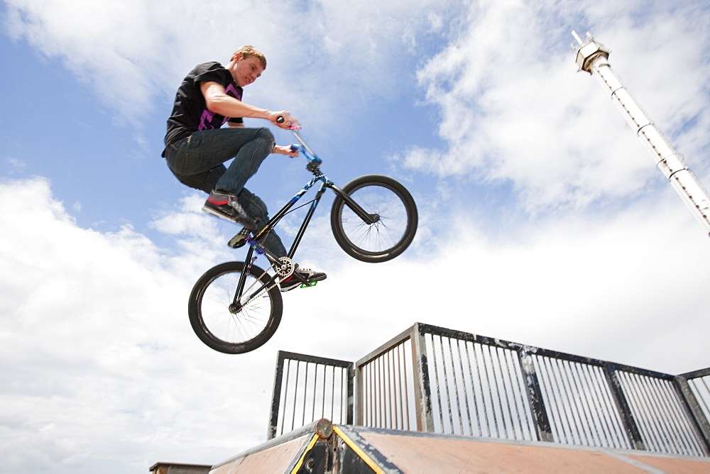 Teenage boys perform aerial stunts on BMX bikes at a BMX park in Rhyl, North Wales, United Kingdom, Europe