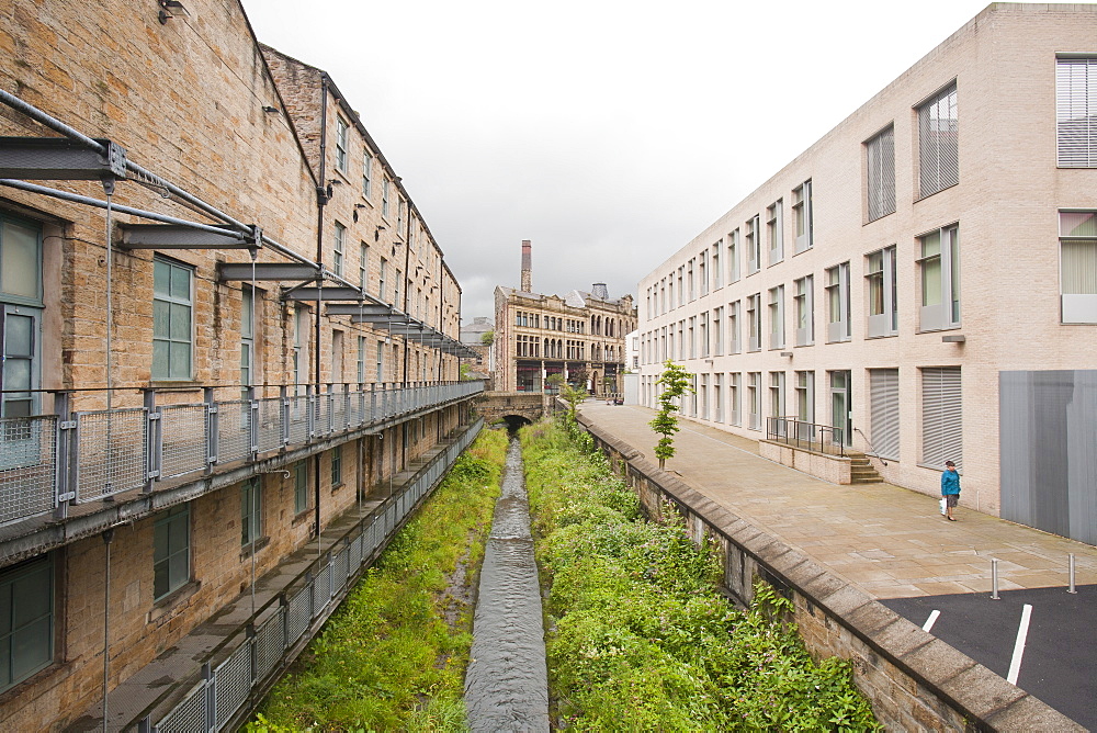 A straightened, channelised water course through Burnley Town centre between old buildings and the modern job centre, Lancashire, England, United Kingdom, Europe