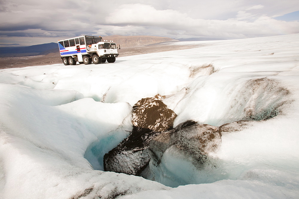 A twenty ton ice explorer truck owned and run by Arngrimur Hermannsson ( Arni), next to a sink hole for meltwater (moulin), Langjokull ice cap, Iceland, Polar Regions