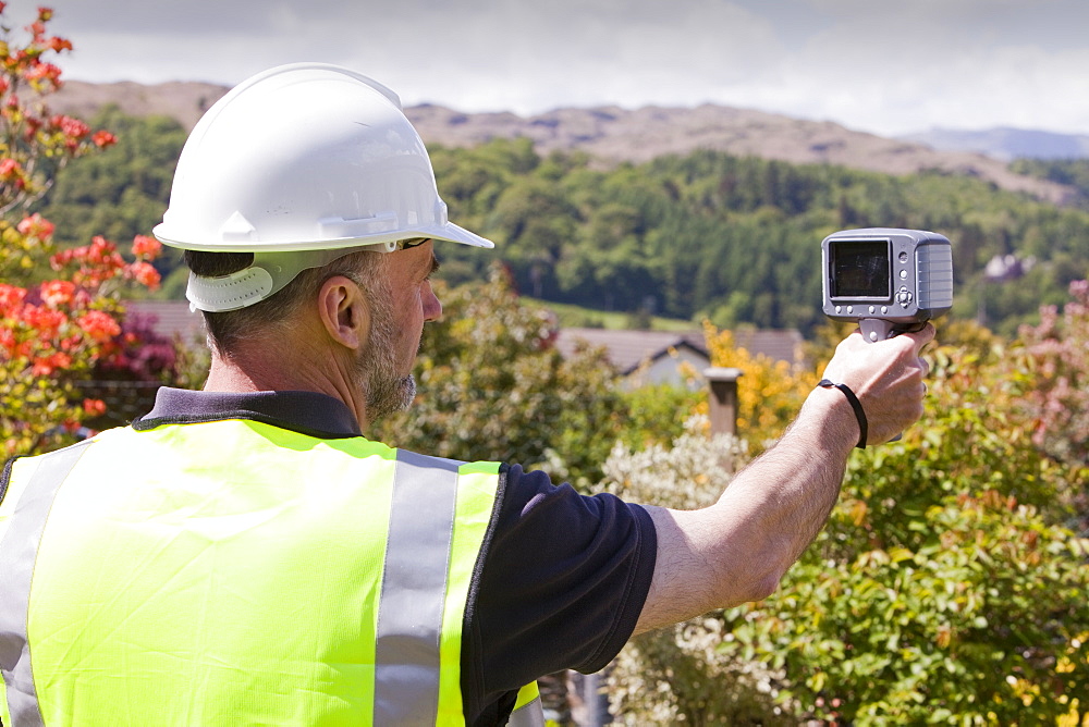 A technician uses a thermal imaging camera to check the thermal efficiency of a house, and where heat is lost from the house, United Kingdom, Europe