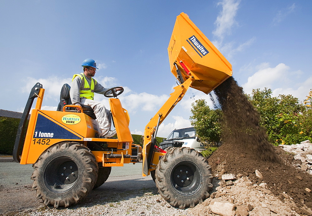 A builder driving a mini dumper truck on a house extension, building job, Ambleside, Cumbria, England, United Kingdom, Europe