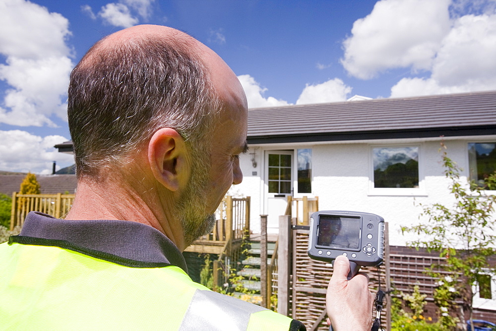 A technician uses a thermal imaging camera to check the thermal efficiency of a house, and where heat is lost from the house, United Kingdom, Europe