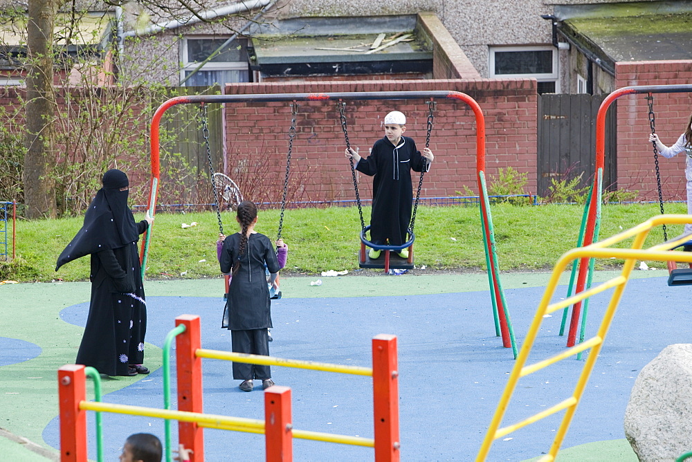 Muslims including a women in a burkha in a playground in a Muslim area of Blackburn, Lancashire, England, United Kingdom, Europe