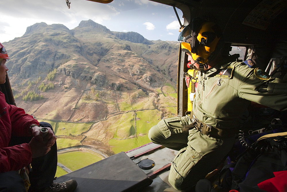 Member of Langdale Ambleside Mountain Rescue team and an RAF winch man in an RAF Sea King helicopter during a rescue in Dungeon Ghyll in the Langdale Pikes Lake District, Cumbria, England, United Kingdom, Europe