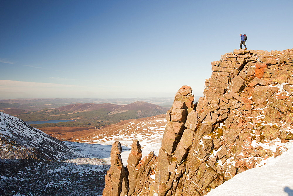 A mountaineer on a rocky granite outcrop above Coire an Lochain in the Cairngorm Mountains, Scotland, United Kingdom, Europe