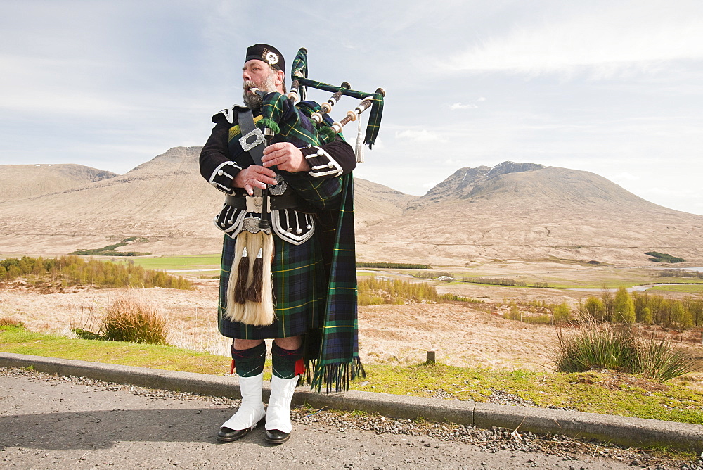 A Scottish piper in traditional dress busking on Rannoch Moor in Argyll, Scotland, United Kingdom, Europe