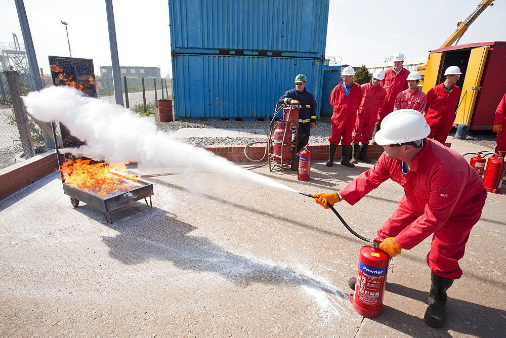 Workers in the offshore industry practise fire fighting with a powder extinguisher as part of an industry training course, Billingham, Teesside, England, United Kingdom, Europe