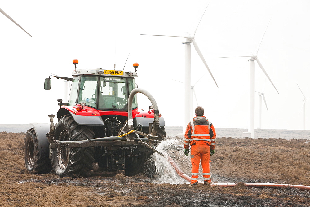 Tractors connected to hose pipes spraying the moorland to damp down the fire on Ogden Moor, near Wainstalls, above Halifax, Yorkshire, England, United Kingdom, Europe